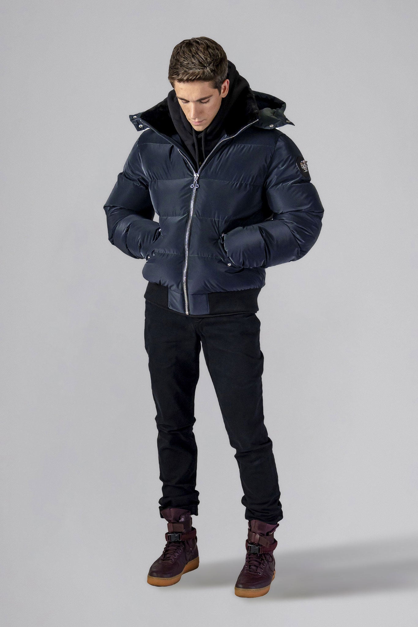 Woodpecker Men's Woody Bomber Winter coat. High-end Canadian designer winter coat for men in "Blue Diamond" colour. Woodpecker cruelty-free winter coat designed in Canada. Men's heavy weight short length premium designer jacket for winter. Superior quality warm winter coat for men. Moose Knuckles, Canada Goose, Mackage, Montcler, Will Poho, Willbird, Nic Bayley. Shiny parka. Stylish winter jacket. Designer winter coat.