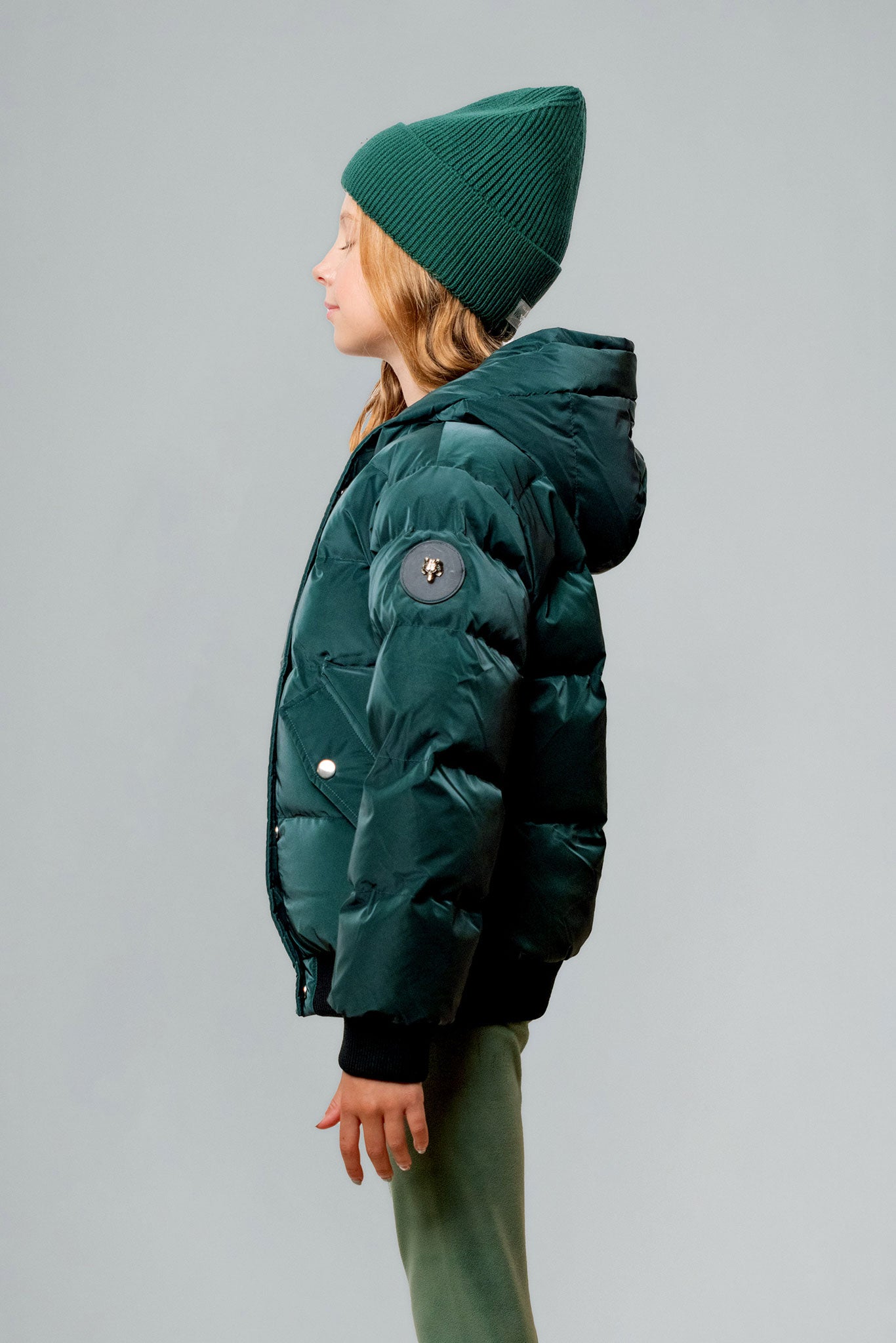 Woodpecker Kids' Chickadee Winter coat. High-end Canadian designer winter coat for Kids in "Green Diamond" colour. Woodpecker cruelty-free winter coat designed in Canada. Kids' heavy weight short length premium designer jacket for winter. Superior quality warm winter coat for kids. Moose Knuckles, Canada Goose, Mackage, Montcler, Will Poho, Willbird, Nic Bayley. Extra warm. Shiny parka. Stylish winter jacket. Designer winter coat.