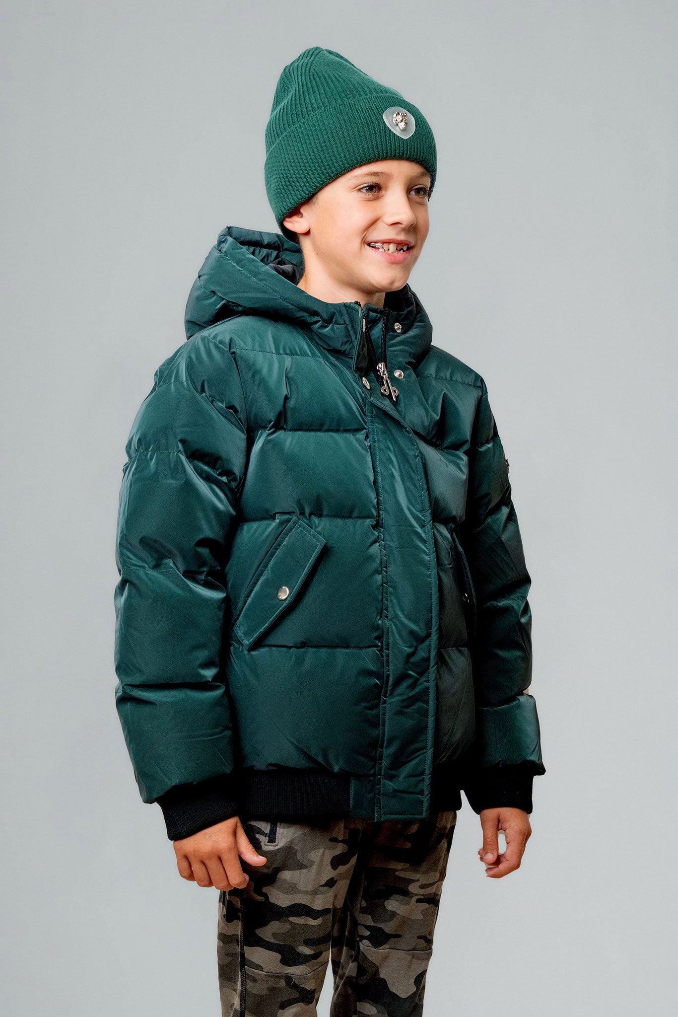 Woodpecker Kids' Chickadee Winter coat. High-end Canadian designer winter coat for Kids in "Green Diamond" colour. Woodpecker cruelty-free winter coat designed in Canada. Kids' heavy weight short length premium designer jacket for winter. Superior quality warm winter coat for kids. Moose Knuckles, Canada Goose, Mackage, Montcler, Will Poho, Willbird, Nic Bayley. Extra warm. Shiny parka. Stylish winter jacket. Designer winter coat.