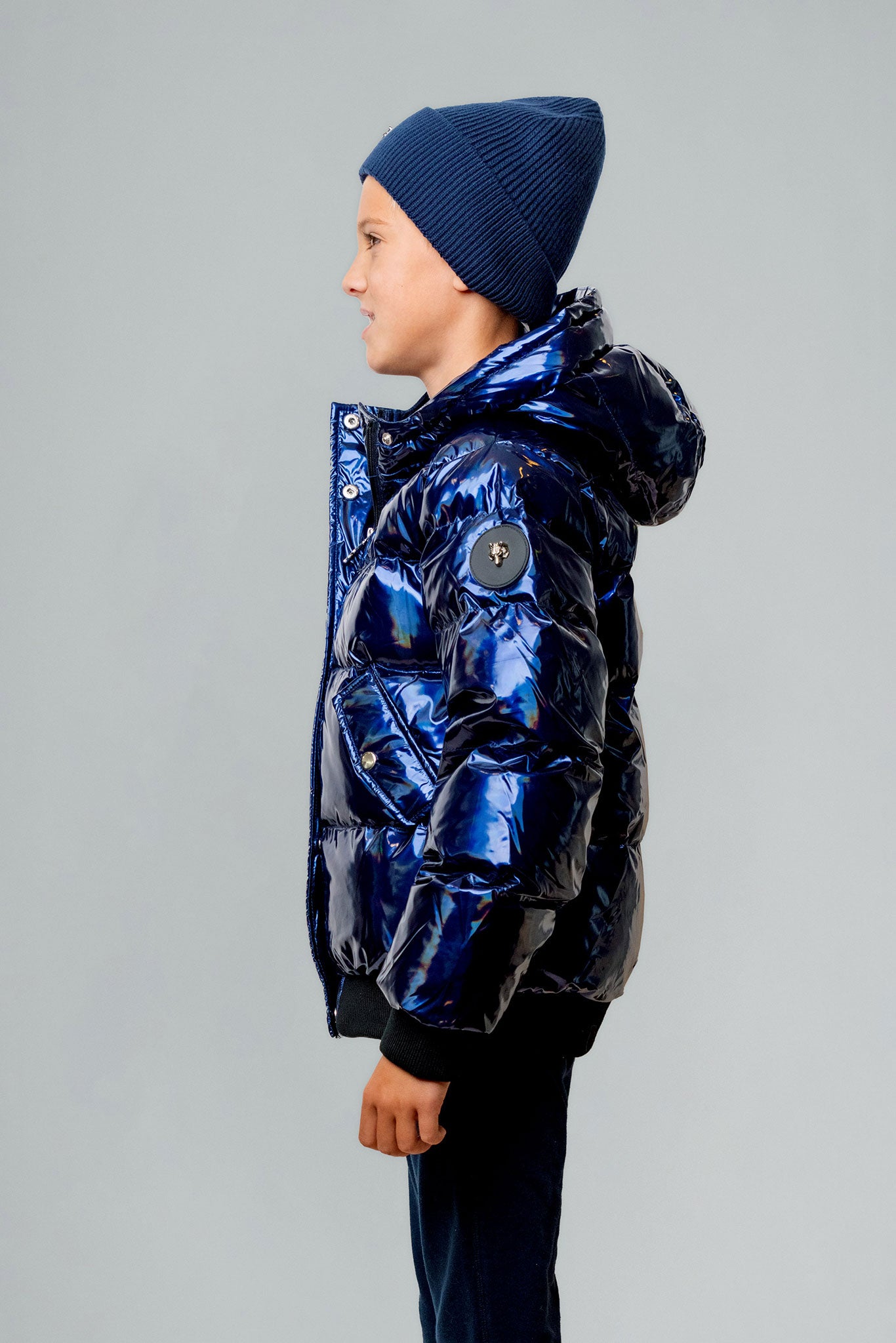 Woodpecker Kids' Chickadee Winter coat. High-end Canadian designer winter coat for Kids in "Oily Blue" colour. Woodpecker cruelty-free winter coat designed in Canada. Kids' heavy weight short length premium designer jacket for winter. Superior quality warm winter coat for kids. Moose Knuckles, Canada Goose, Mackage, Montcler, Will Poho, Willbird, Nic Bayley. Extra warm. Shiny parka. Stylish winter jacket. Designer winter coat.