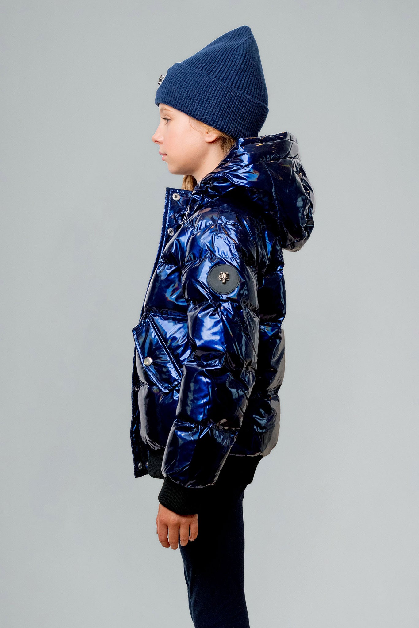 Woodpecker Kids' Chickadee Winter coat. High-end Canadian designer winter coat for Kids in "Oily Blue" colour. Woodpecker cruelty-free winter coat designed in Canada. Kids' heavy weight short length premium designer jacket for winter. Superior quality warm winter coat for kids. Moose Knuckles, Canada Goose, Mackage, Montcler, Will Poho, Willbird, Nic Bayley. Extra warm. Shiny parka. Stylish winter jacket. Designer winter coat.